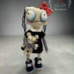 Ręcznie wykonana lalka amigurumi w czarnej sukience z białym kołnierzykiem, trzymająca małego misia.